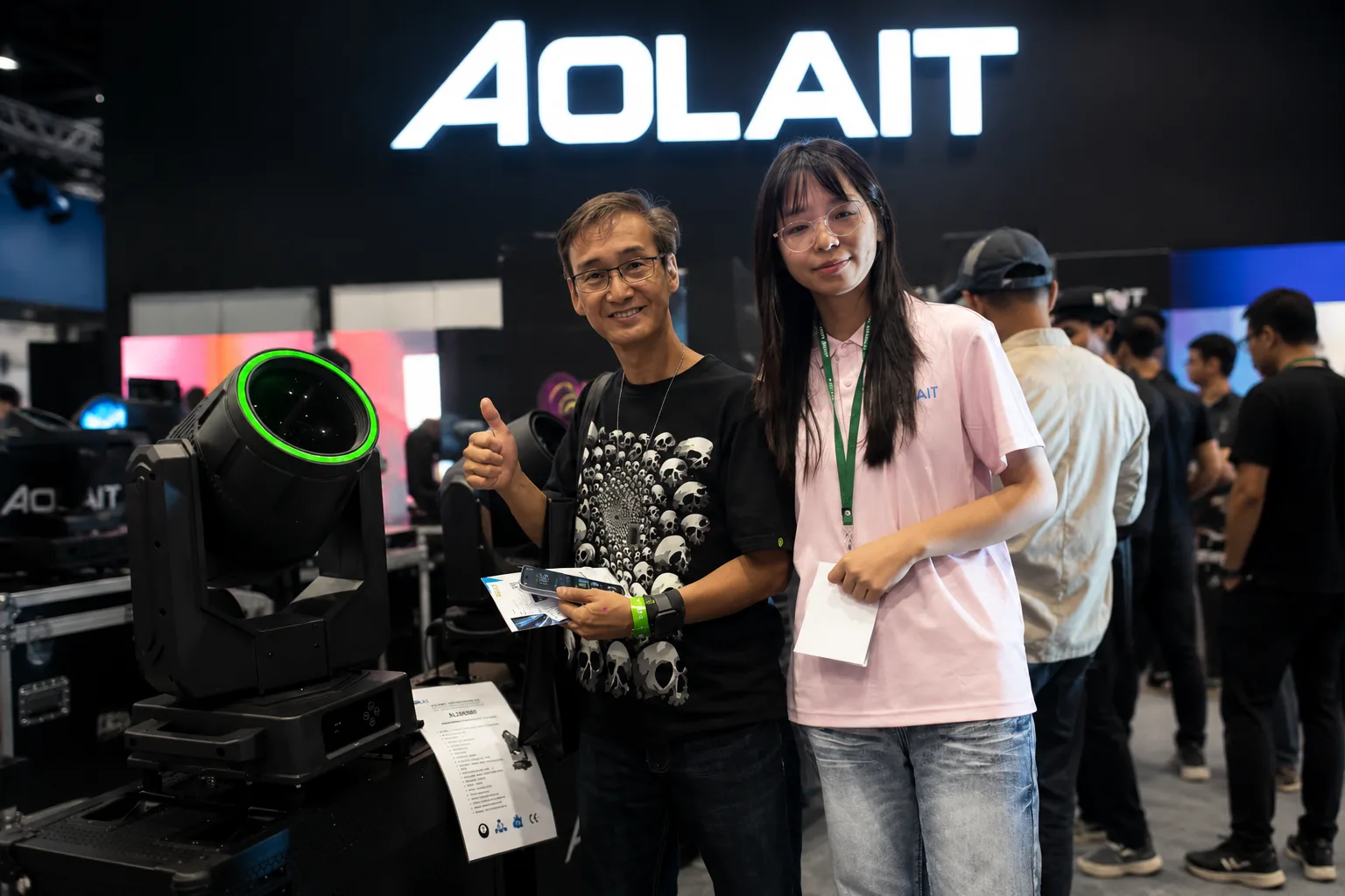 AOLAIT representative discussing a moving head fixture with an exhibition visitor