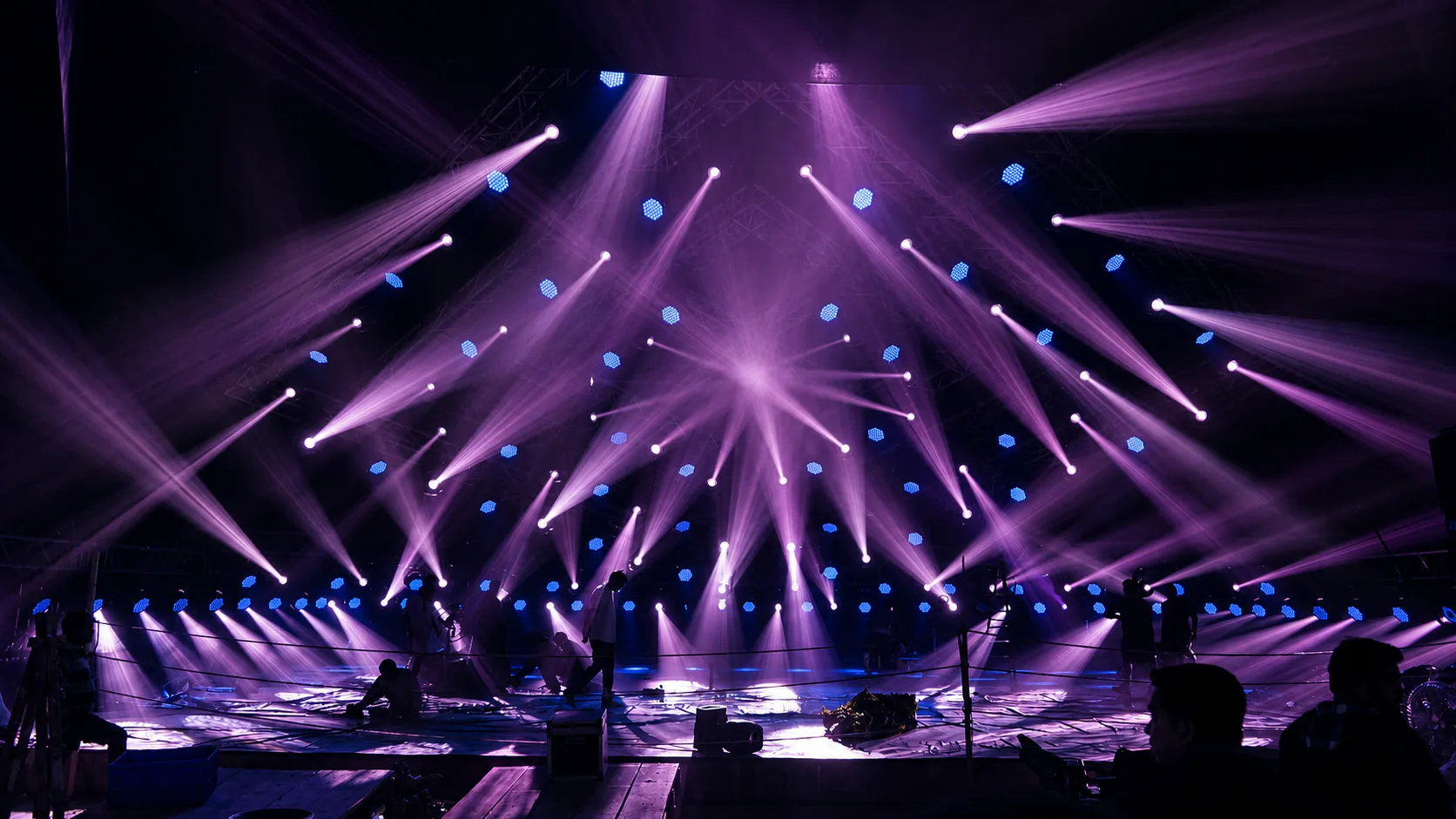 Purple LED moving head beams covering a large stage during setup