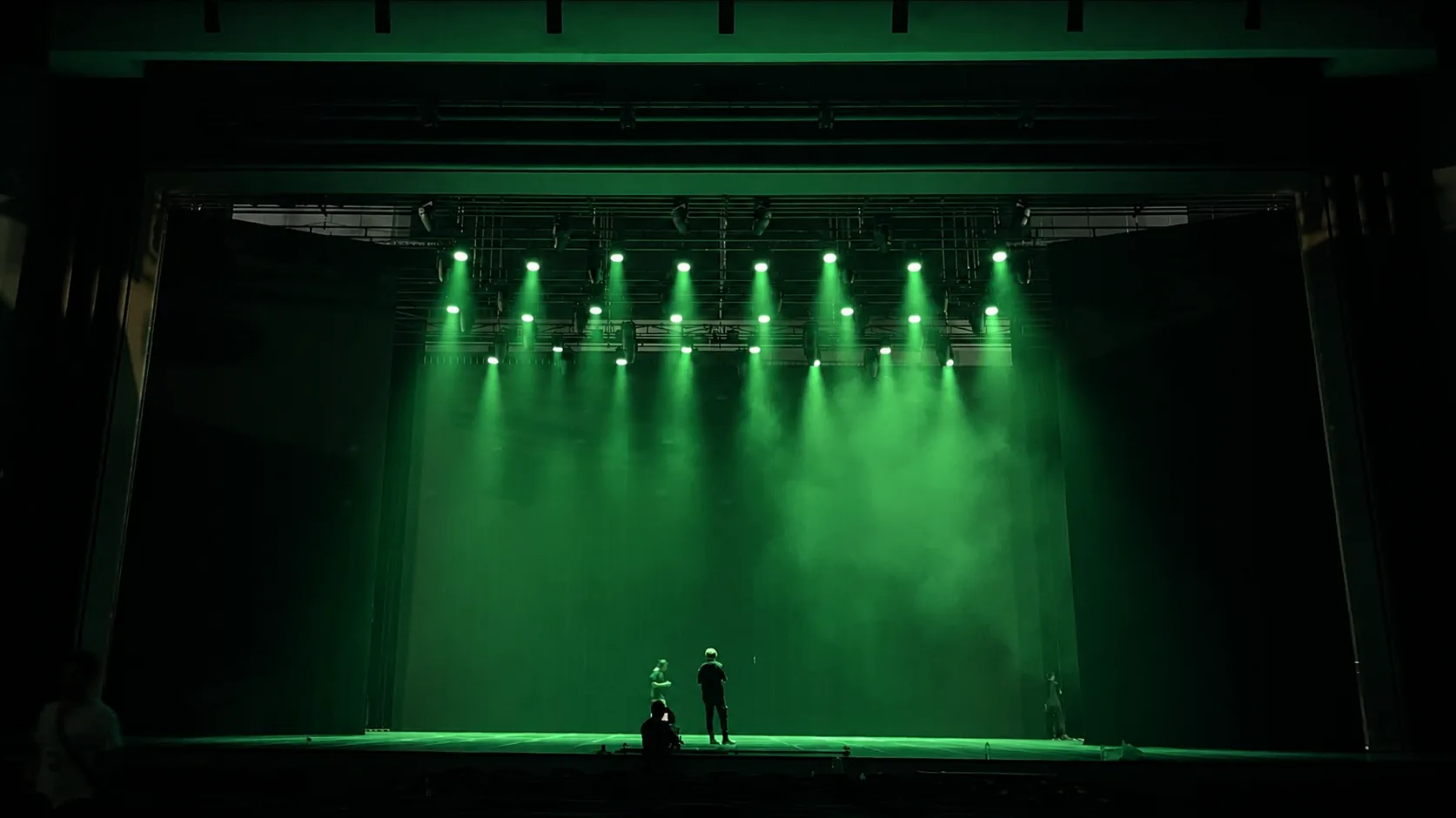 Green wash beams illuminating a theatre stage during a lighting setup