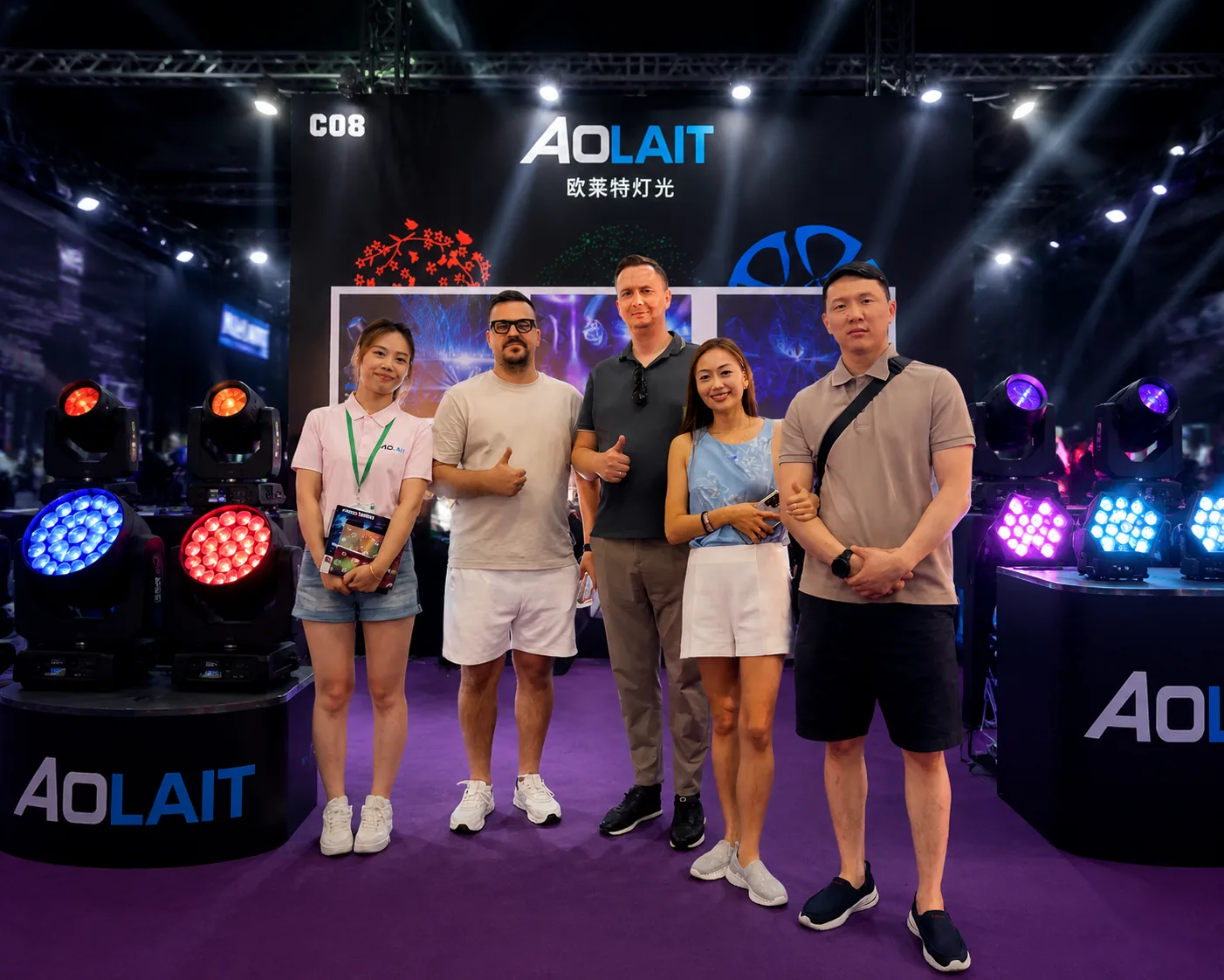 Aolait team members and exhibition visitors standing among illuminated moving head fixtures at the Aolait booth